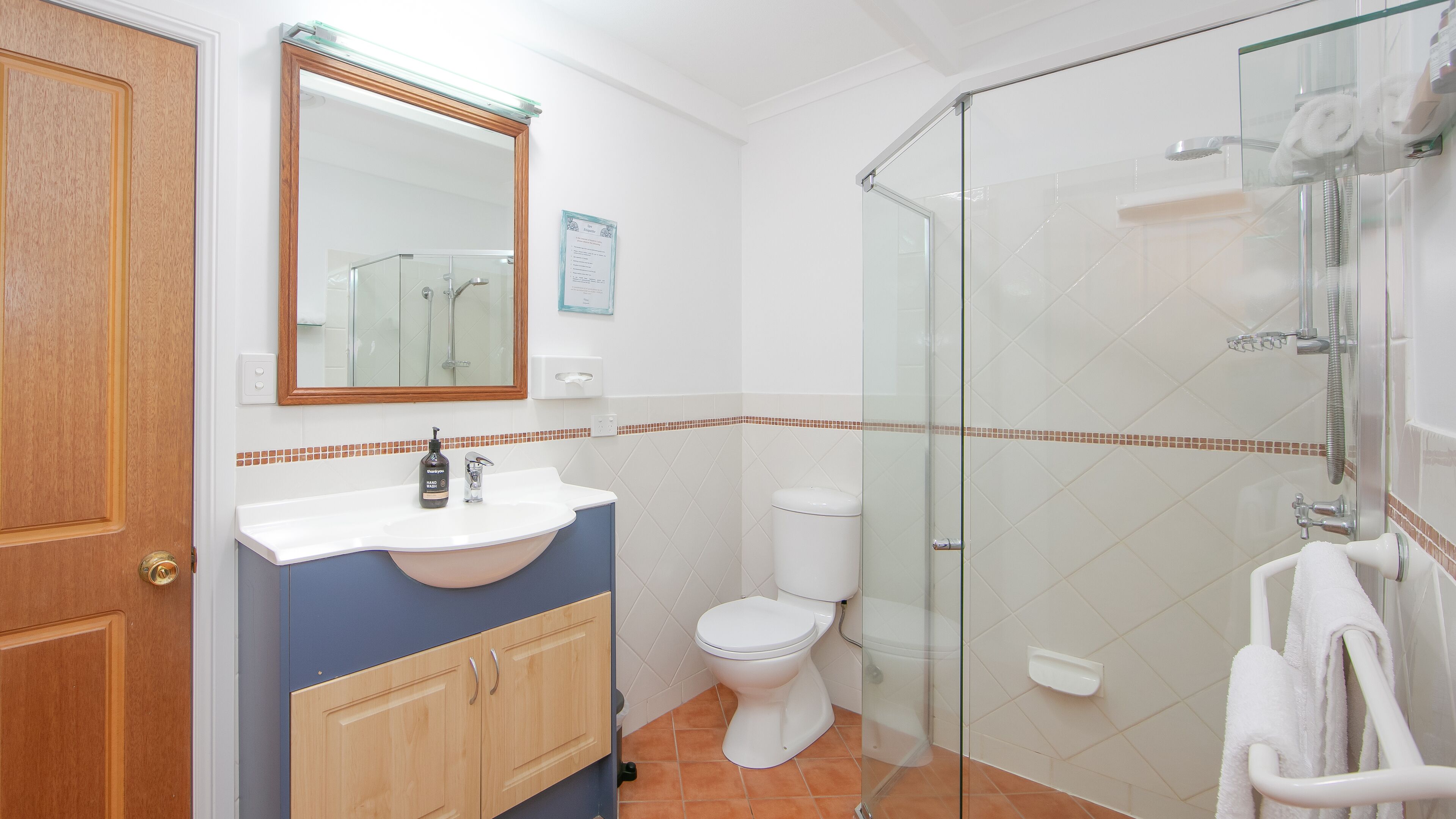 A bathroom with a sink, toilet, and glass shower enclosure.