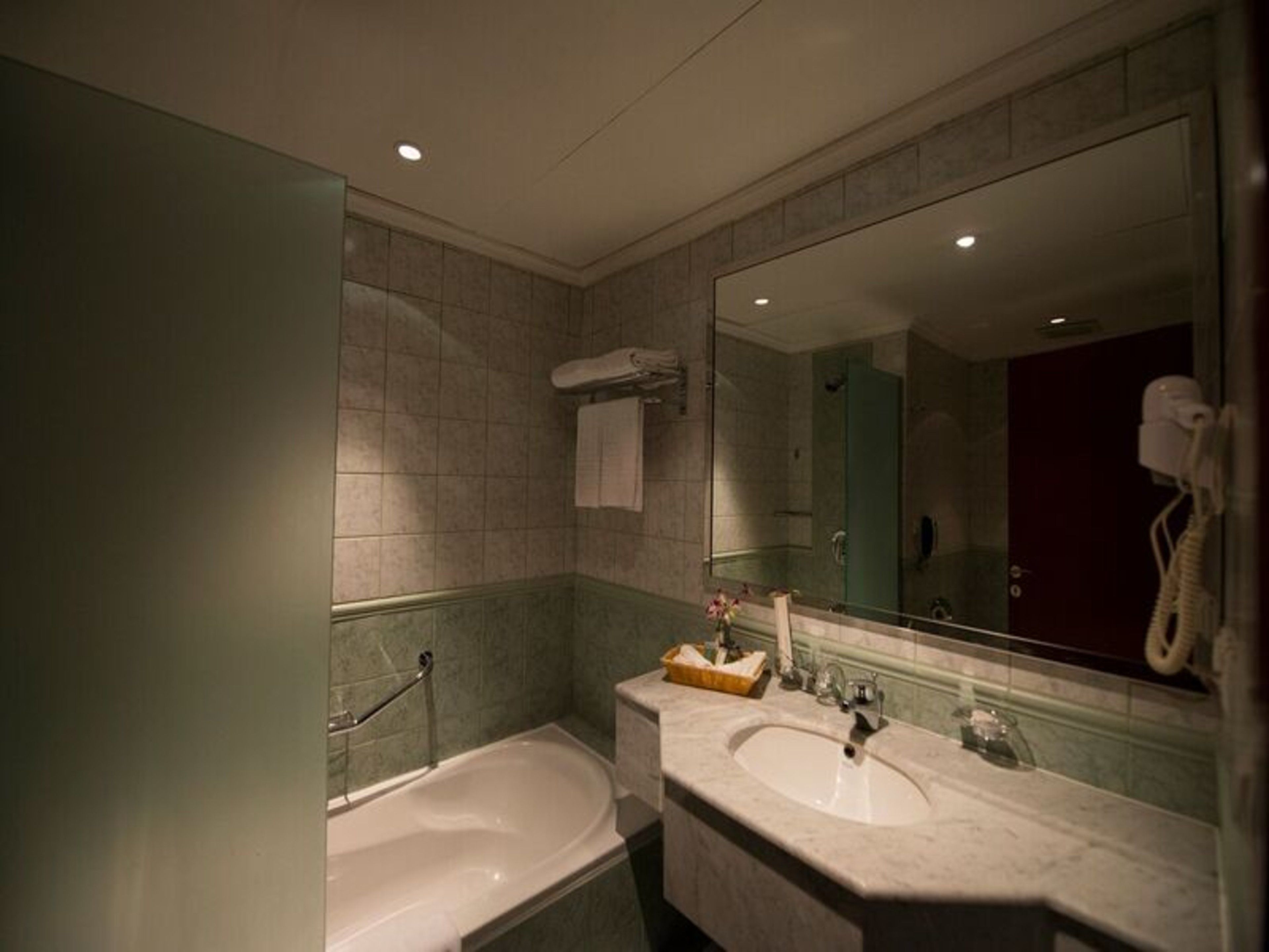 Un baño con dos lavabos, una bañera y un espejo grande.