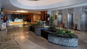A modern hotel lobby with a reception desk, elevators, and a central water feature. - Executives Hotel - Olaya (Riyadh)