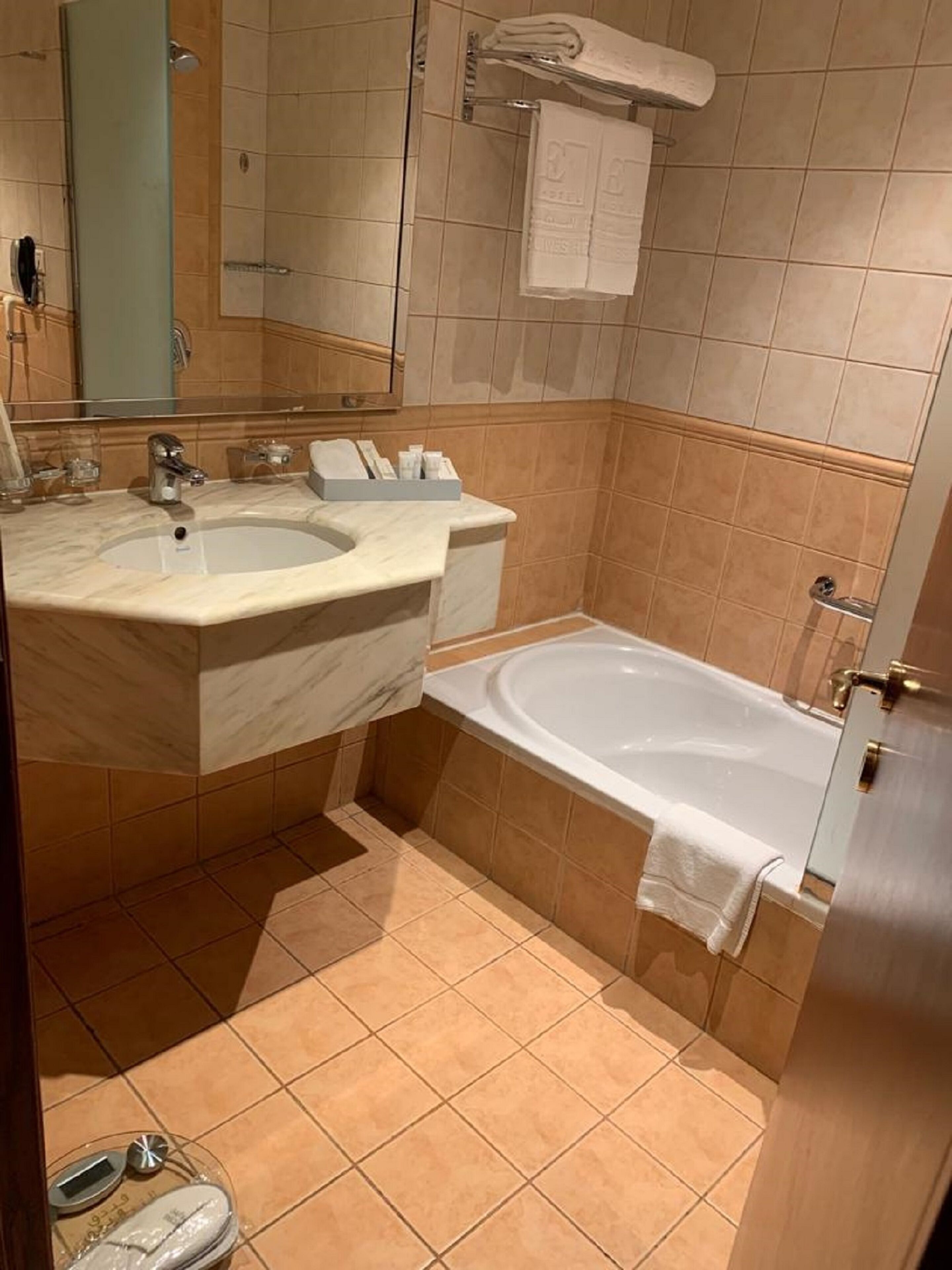 A bathroom with a sink, mirror, and bathtub.