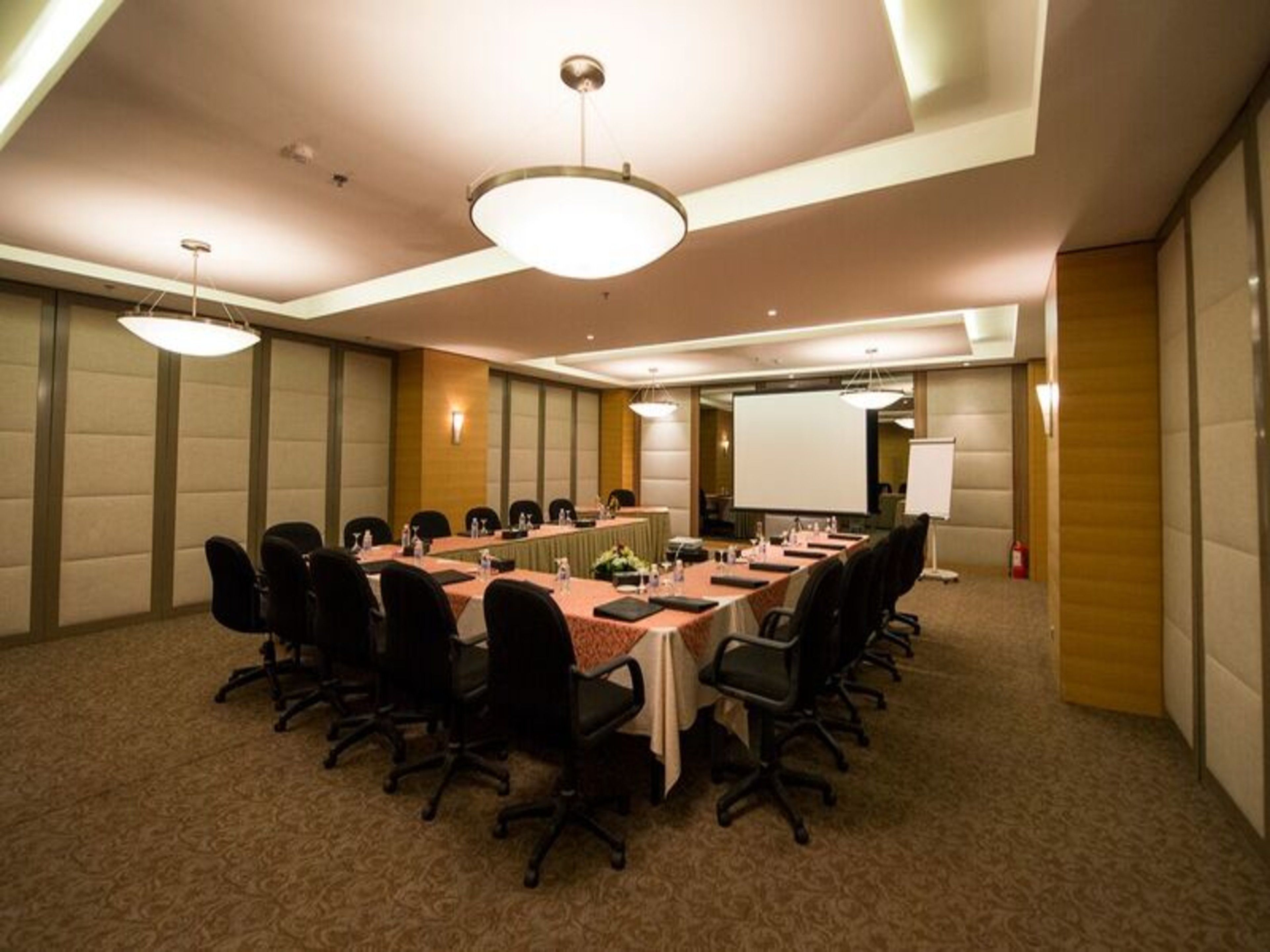 A conference room with a long table, chairs, a projector screen, and a whiteboard.