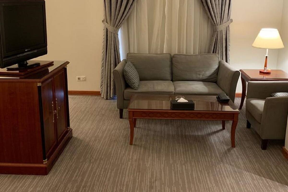A living room with a sofa, a coffee table, a TV on a cabinet, and a lamp.
