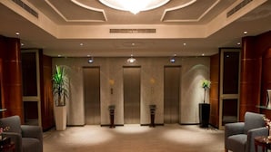 A spacious lobby with a high ceiling, two elevators, and a large central chandelier. - Executives Hotel - Olaya (Riyadh)