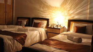 A hotel room with two beds, a nightstand with a lamp, and a wooden wardrobe. - Arab Tower Hotel (Amman)