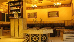 A lobby with a central decorative fountain, a seating area, and a display of items on shelves. - Arab Tower Hotel (Amman)