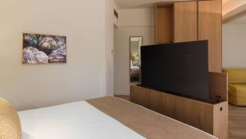 Una habitación de hotel moderna con una cama, un televisor de pantalla plana, un armario de madera y un cuadro en la pared.