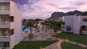 A hotel with a pool area, outdoor seating, and a view of mountains. - Leonardo Kolymbia Resort - All Inclusive (Rhodes)