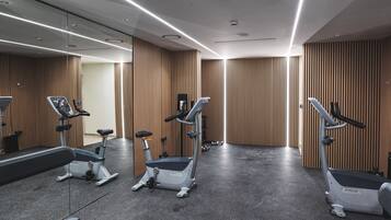 A modern gym with treadmills, elliptical machines, and a mirrored wall.