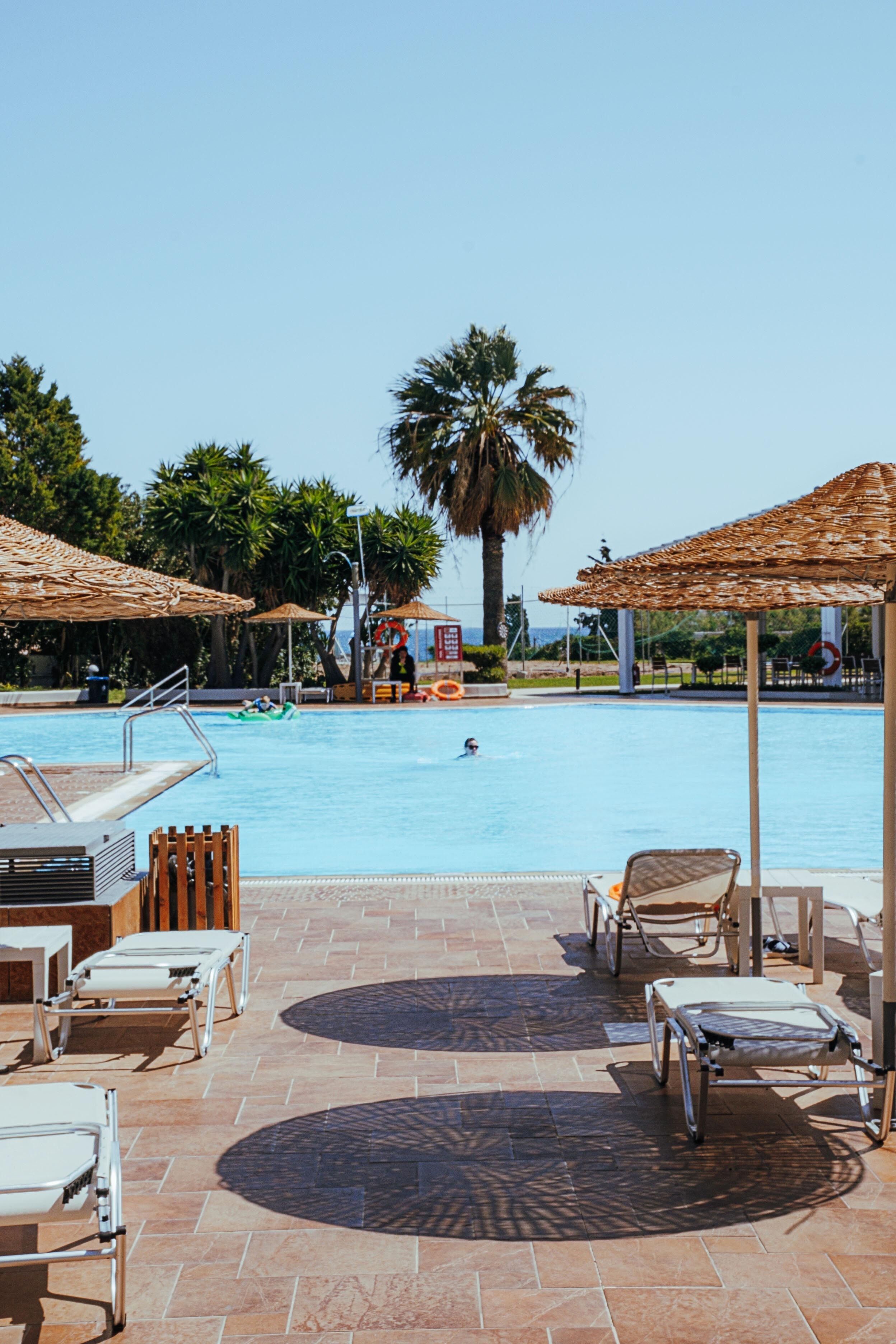 A pool area with lounge chairs, umbrellas, and a lifeguard tower.