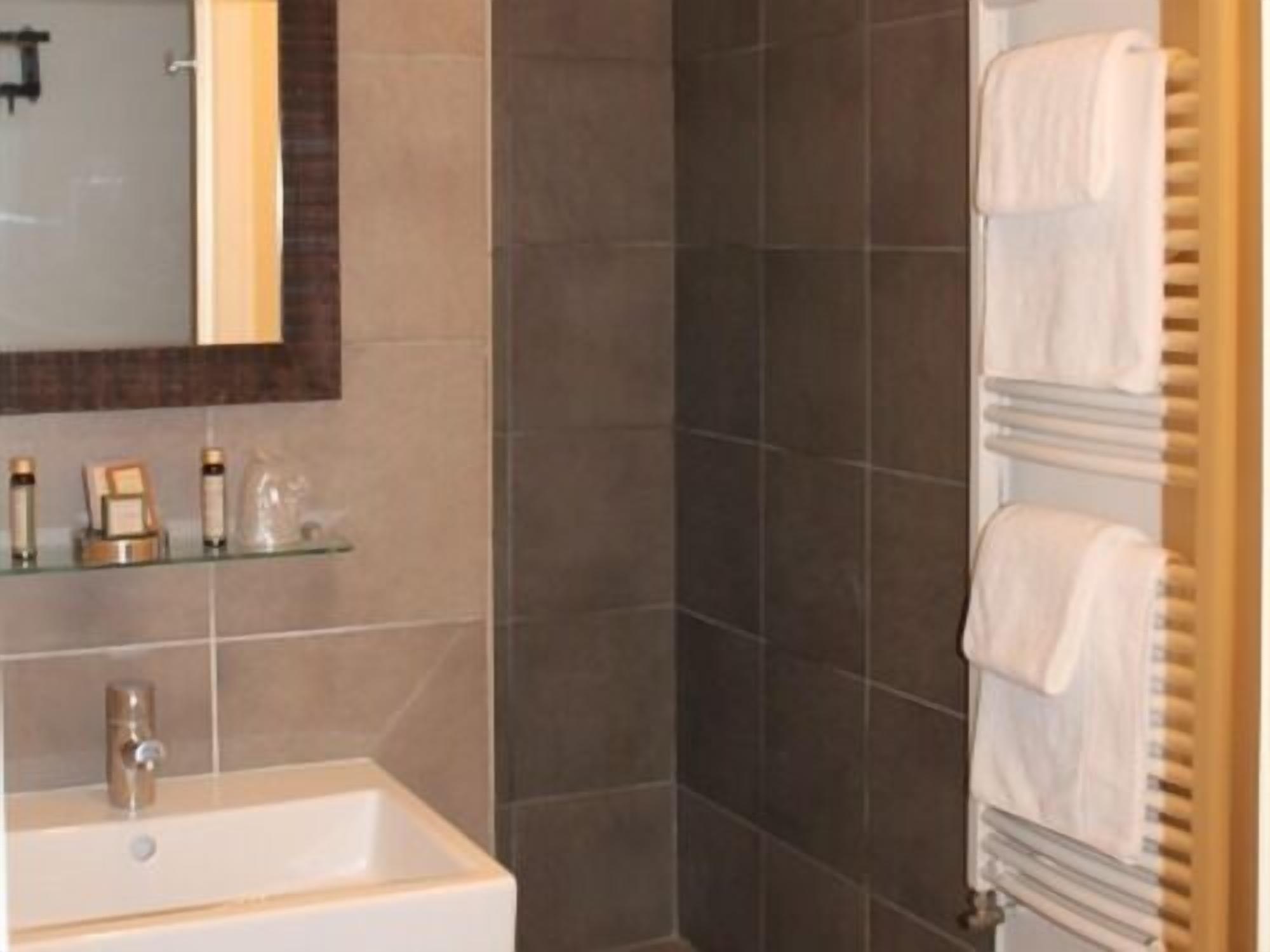 A bathroom with a large mirror, a white sink, and a towel rack with multiple towels.