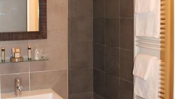 A bathroom with a large mirror, a white sink, and a towel rack with multiple towels.