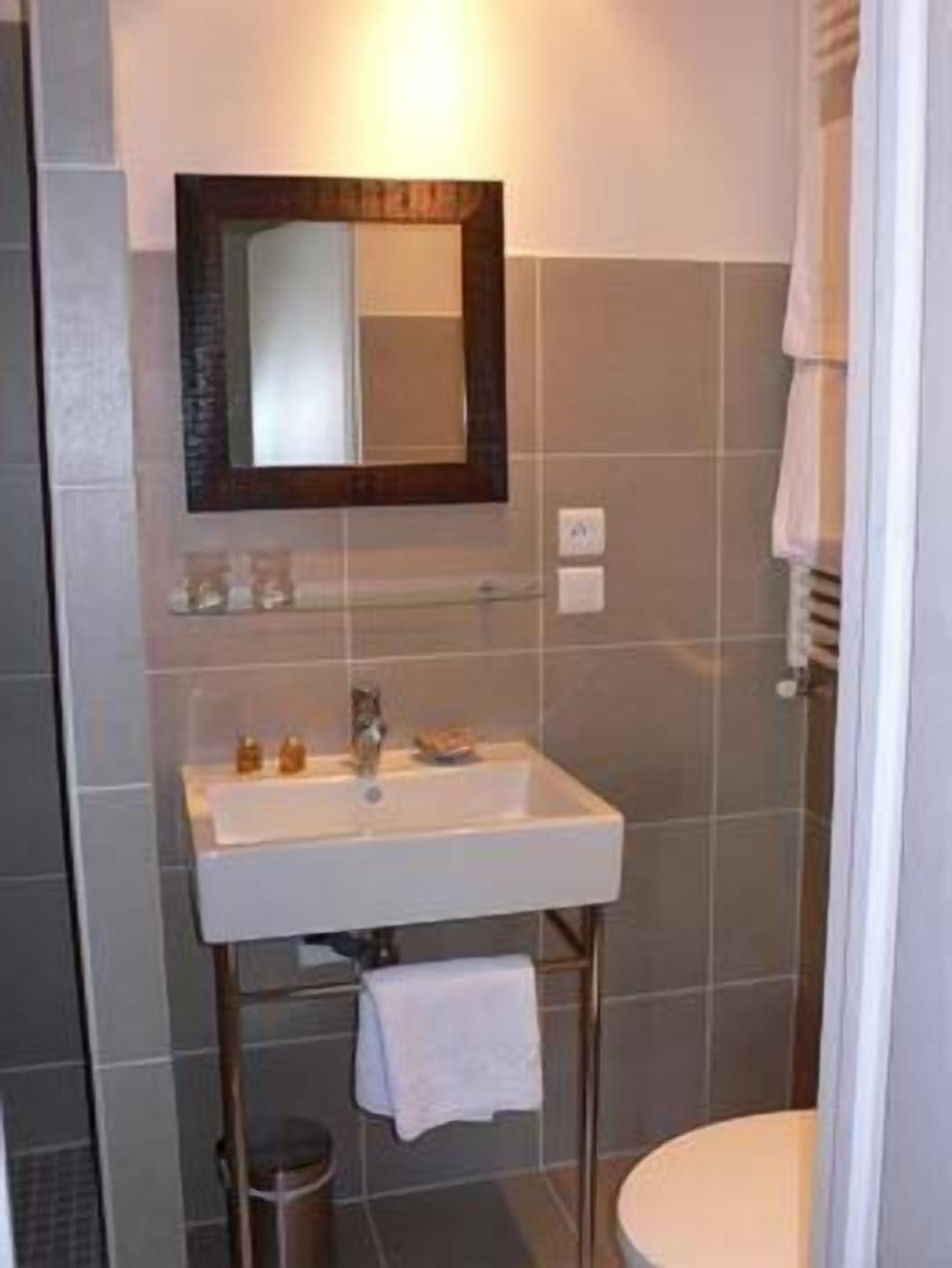 A bathroom with a white sink, a mirror, and a towel rack.