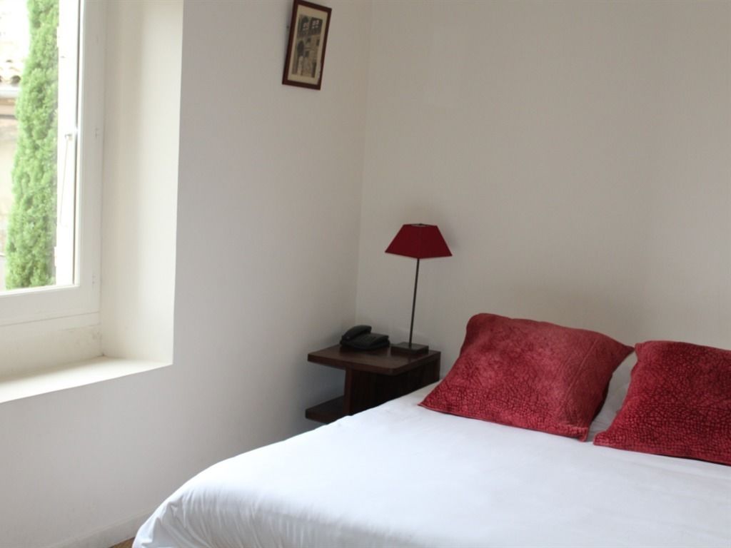 Une chambre à coucher avec un lit, une table de chevet avec une lampe et une fenêtre.