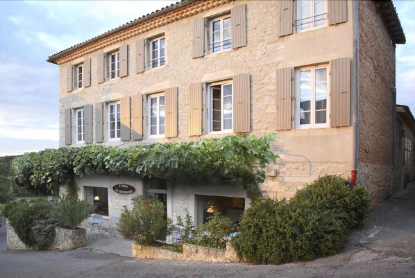 A two-story building with a stone facade, wooden shutters, and a vine-covered entrance. - Hôtel de Mirmande (Mirmande)