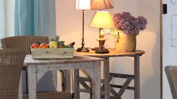 Una mesa de madera rústica con una cesta de frutas, una lámpara y un jarrón con flores.