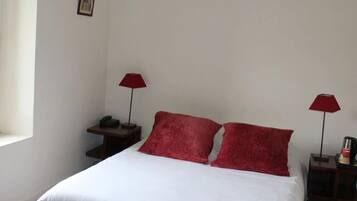 A simple, clean room with a bed, two red lamps, a nightstand, and a small table with a phone.