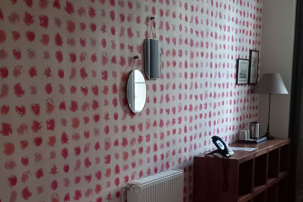 Une chambre d’hôtel avec un lit, un bureau, un miroir et un radiateur.