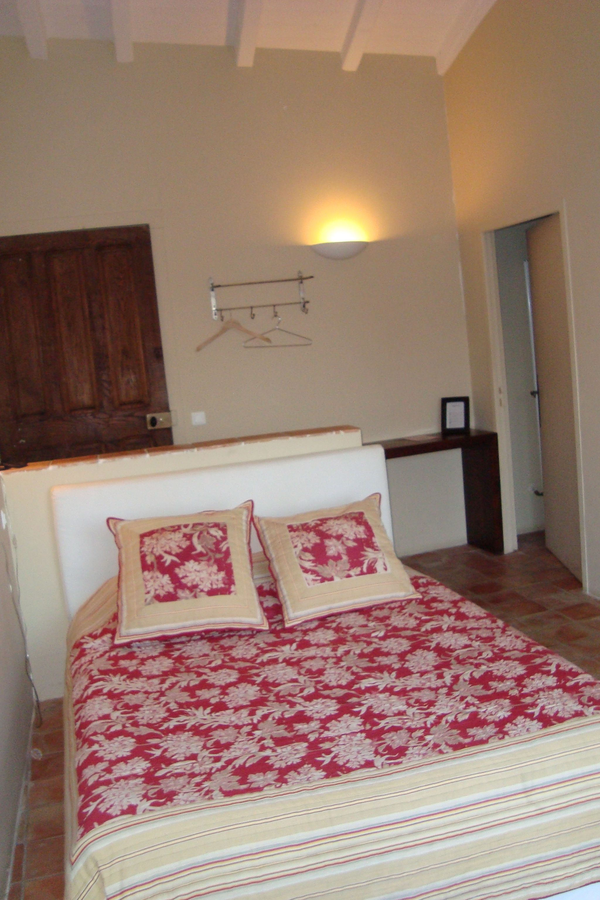 A bedroom with a bed, a wall-mounted light, and a door.