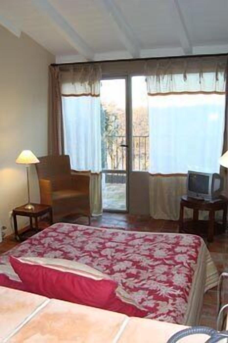 Una habitación de hotel con cama, una silla, un televisor y vista al exterior.