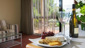 Una mesa de comedor con un plato de queso, galletas y uvas, una botella de vino y una copa de vino.