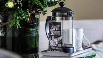A tray with a coffee maker, a mug, and a decorative item on a glass table.