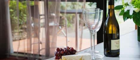 A table with a bottle of wine, a glass, a plate with cheese, grapes, and crackers.