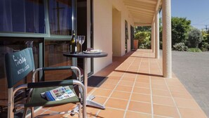 Un espacio de estar al aire libre cubierto, con una mesa, una silla y una botella de vino.