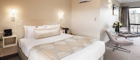 A hotel room with a bed, bedside tables, a chair, and a window with curtains.