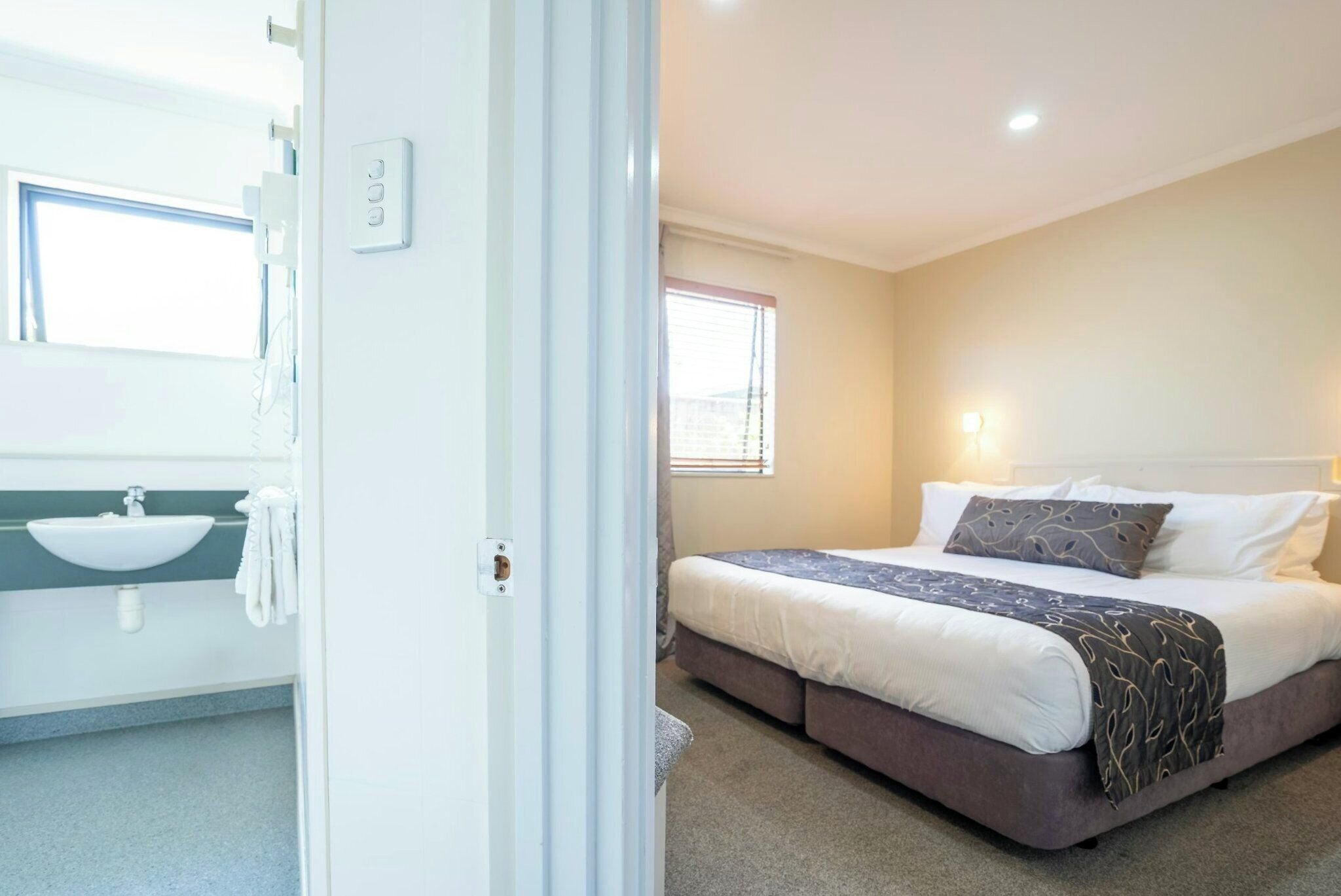 Un dormitorio con cama, ventana y baño con lavamanos.