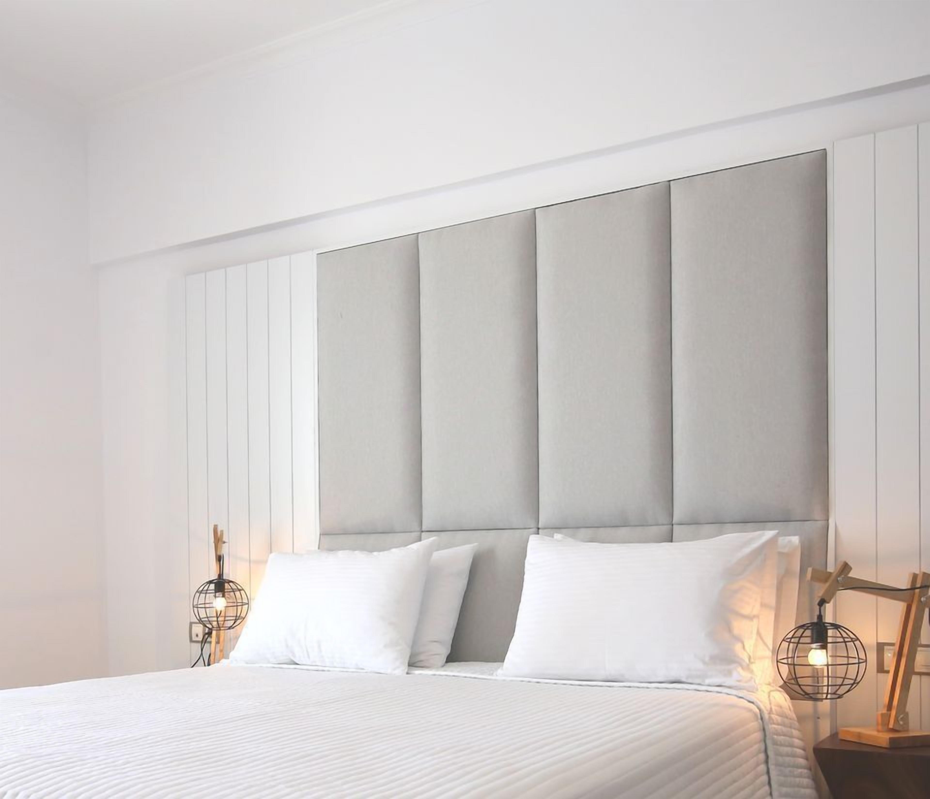 Un dormitorio moderno con una cama grande, cabecera acolchada y dos lámparas de noche.