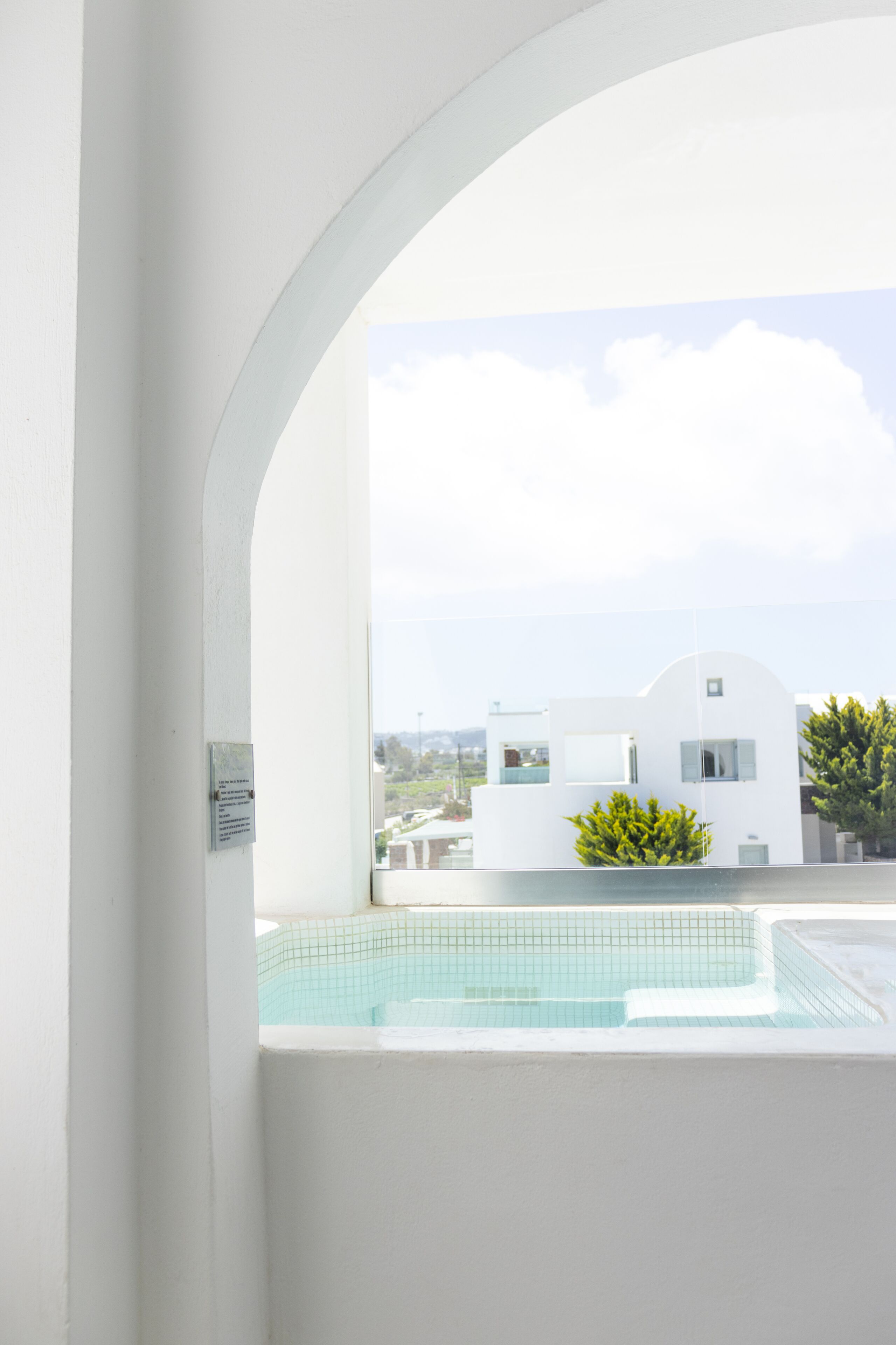 Un edificio moderno con piscina, fachada blanca y cielo despejado.