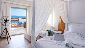 A bedroom with a bed, a laptop, a bedside table, and a view of a pool and outdoor seating area.