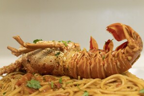 A lobster with a fork on top of a plate of spaghetti. - Astro Palace Hotel & Spa (Santorini)