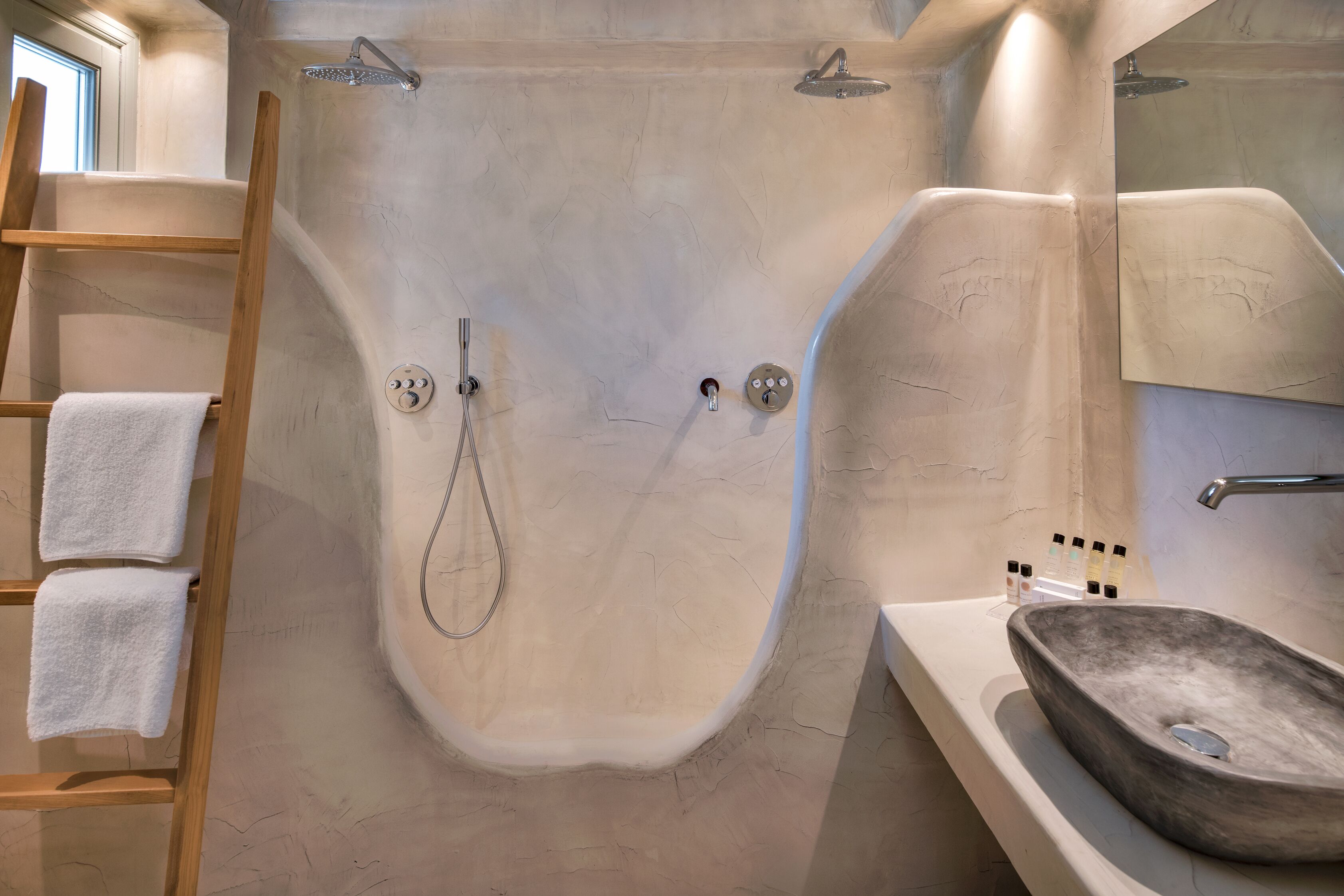 A modern bathroom with a freestanding bathtub, a wooden ladder, and a large mirror.