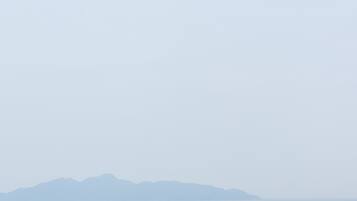 Un edificio blanco con techo curvo, con vista a un cuerpo de agua y montañas distantes.