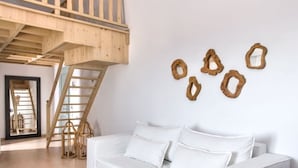 A modern living room with a white sofa, a wooden coffee table, and a wooden staircase.