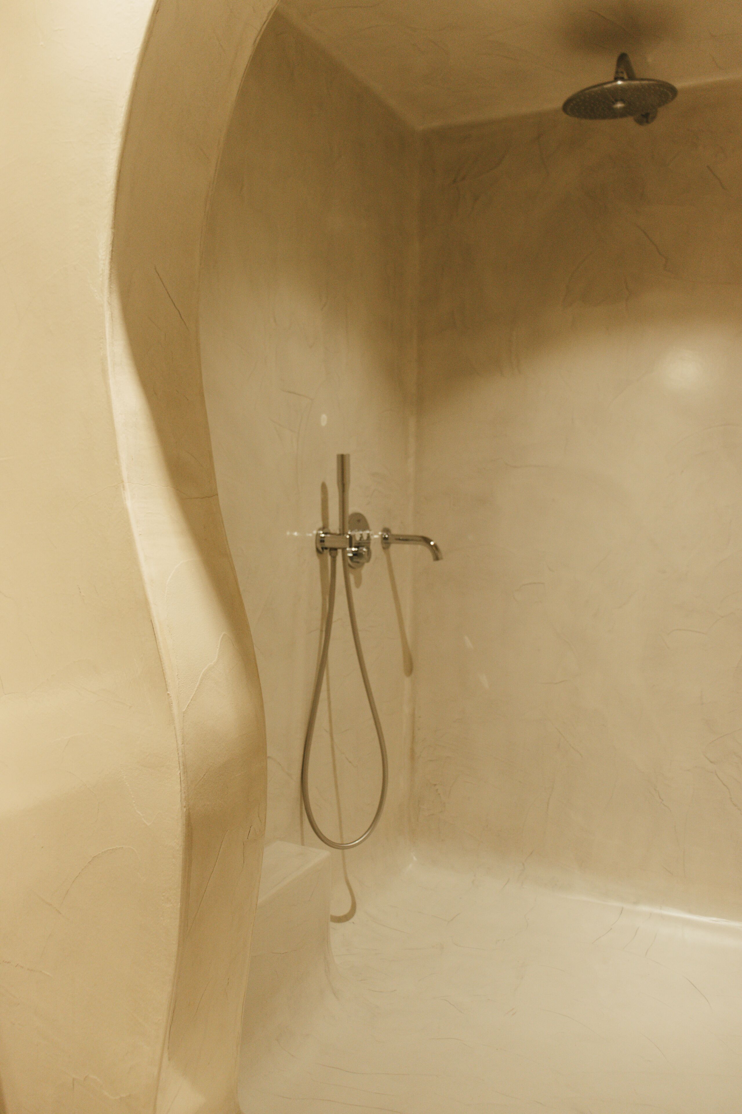 Een douche met een gebogen wand en een handdouche.