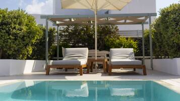 A swimming pool with two lounge chairs and a canopy.