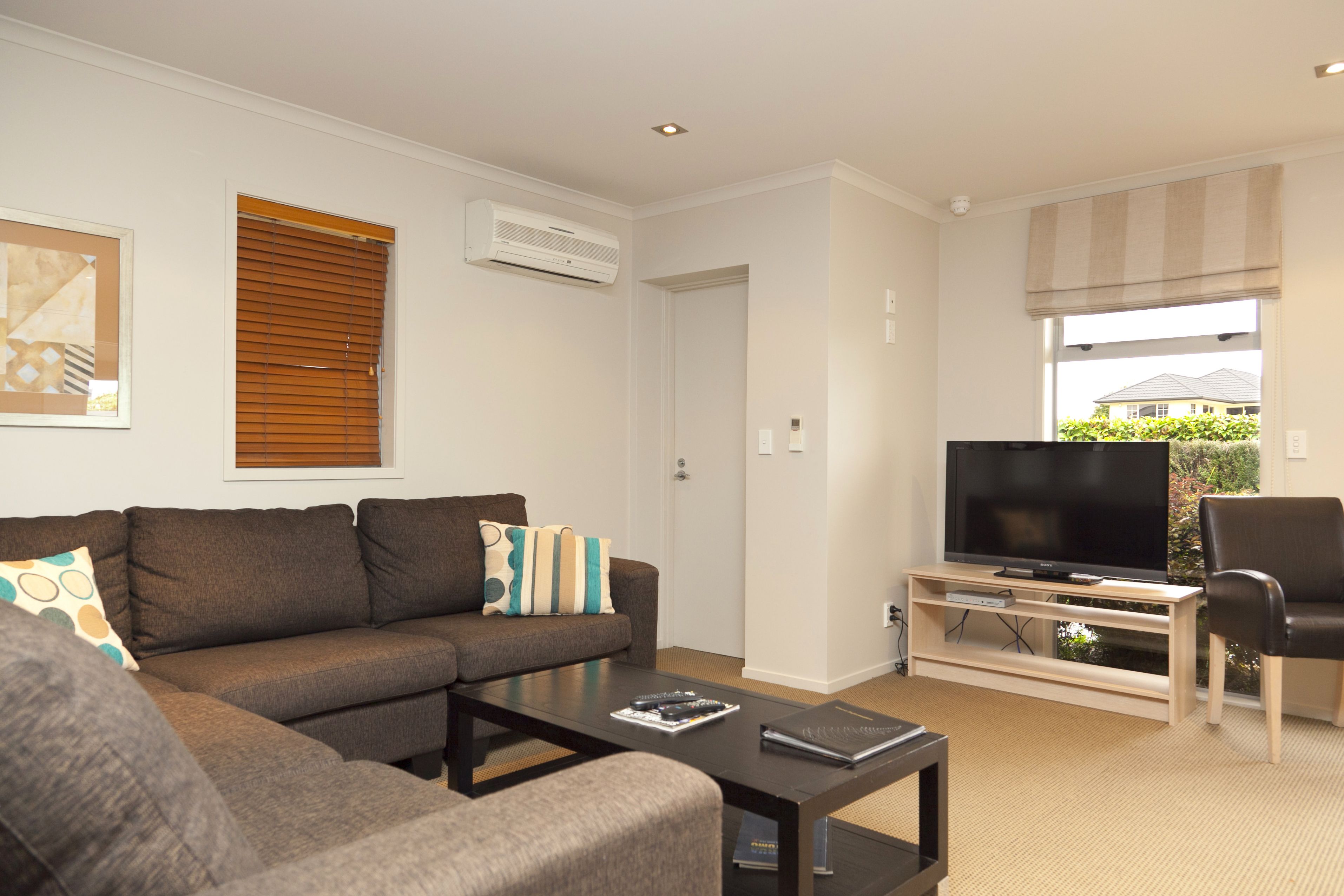 A living room with a sofa, coffee table, TV stand, and a chair.