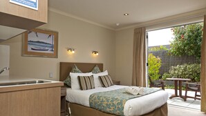 A hotel room with a bed, a small desk, a sink, and a view of the outdoors. - Beechtree Motel (Taupo)