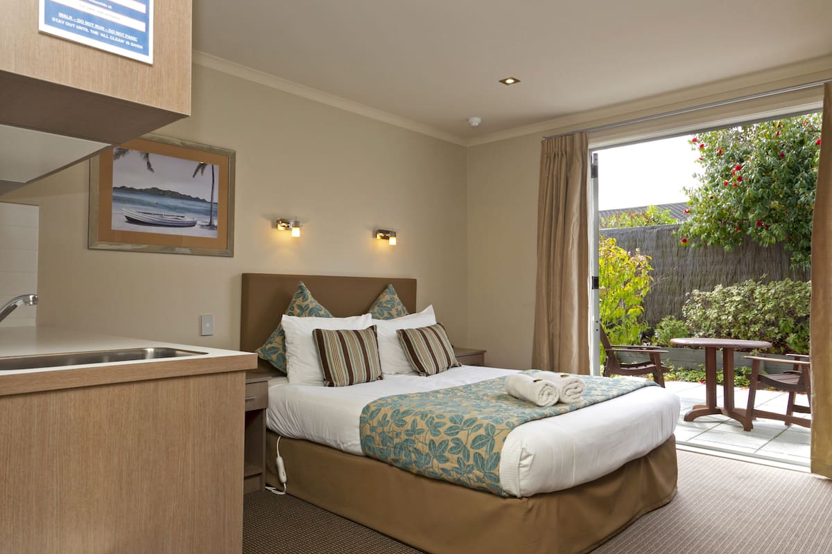 A hotel room with a bed, a small desk, a sink, and a view of the outdoors.