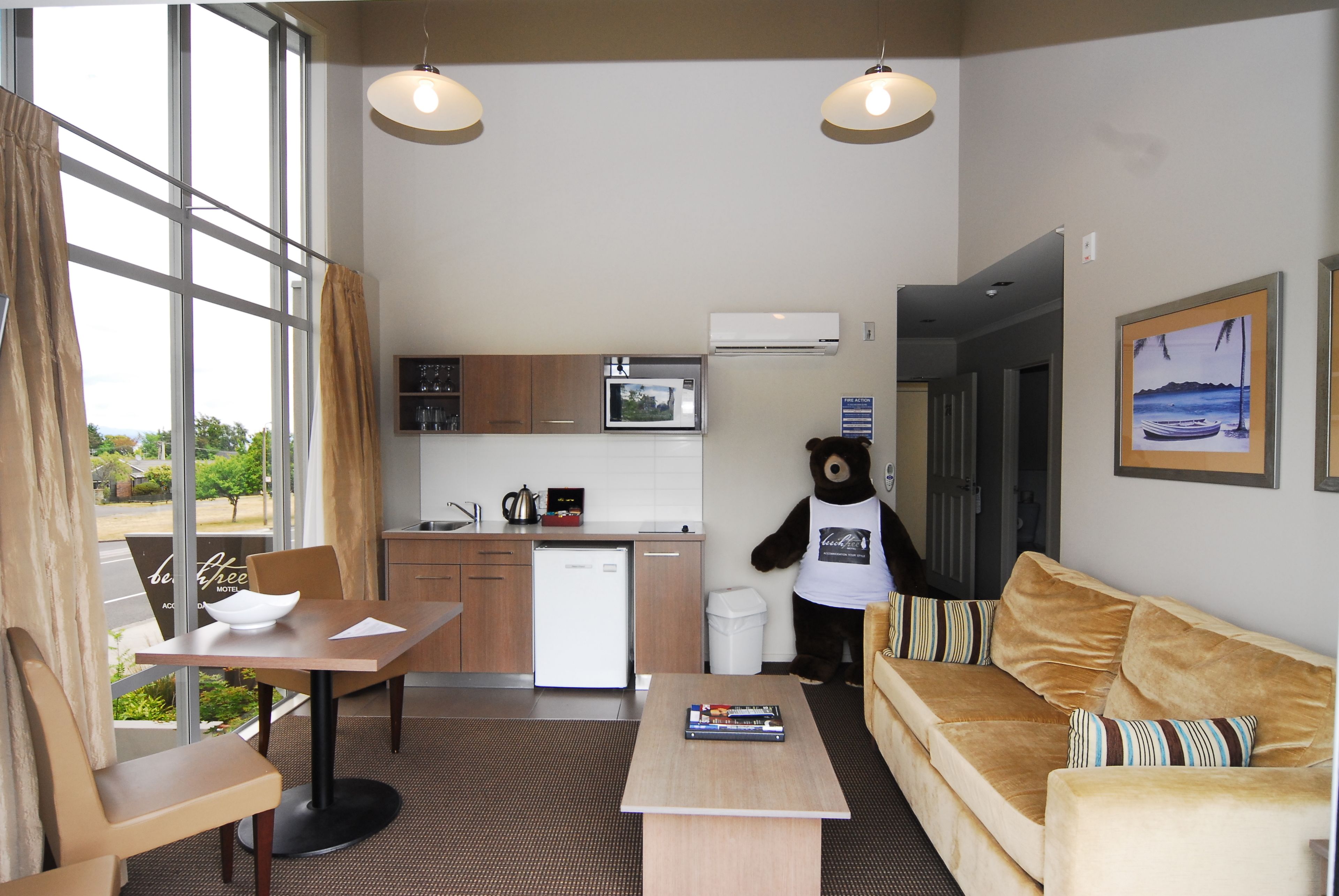 Een knus verblijf met een kitchenette, een bank, een eettafel en een beer mascotte.