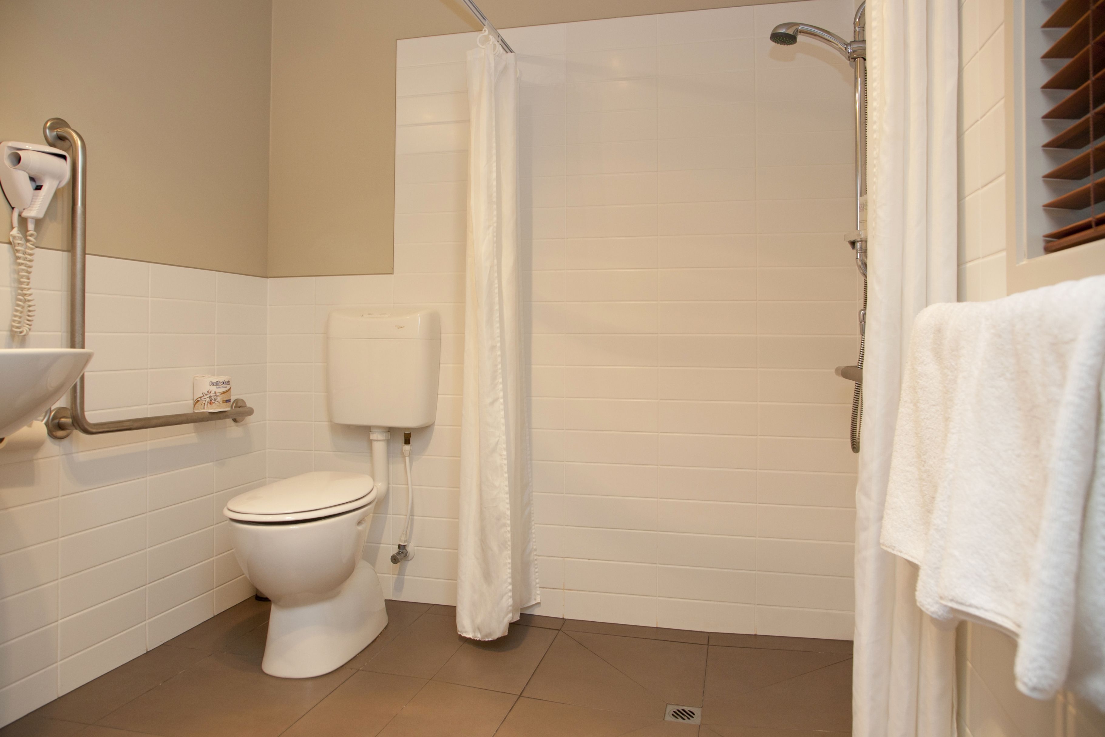 Un baño con inodoro, ducha y toallero.