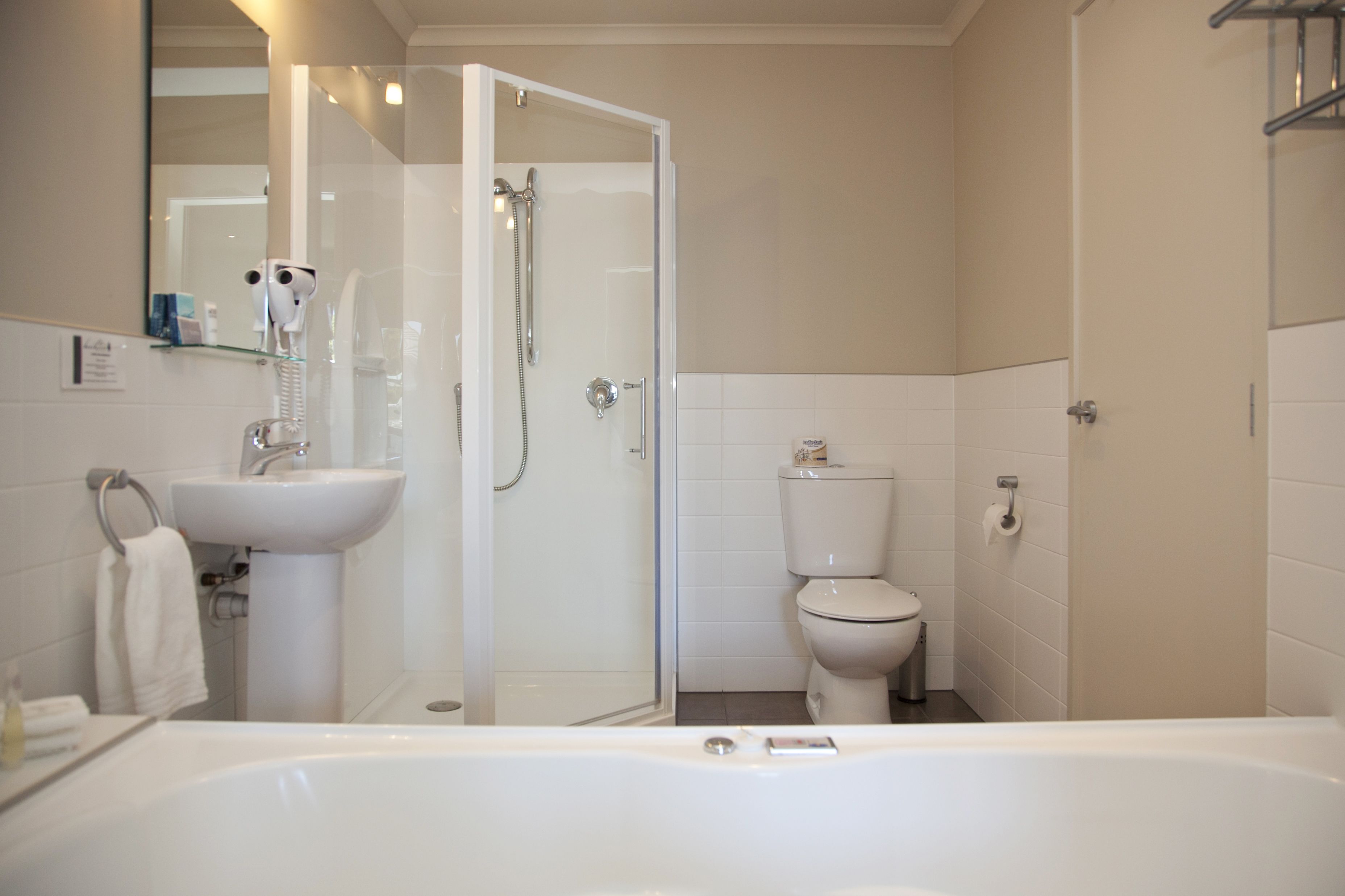 A modern bathroom with a bathtub, a glass-enclosed shower, a toilet, and a sink.