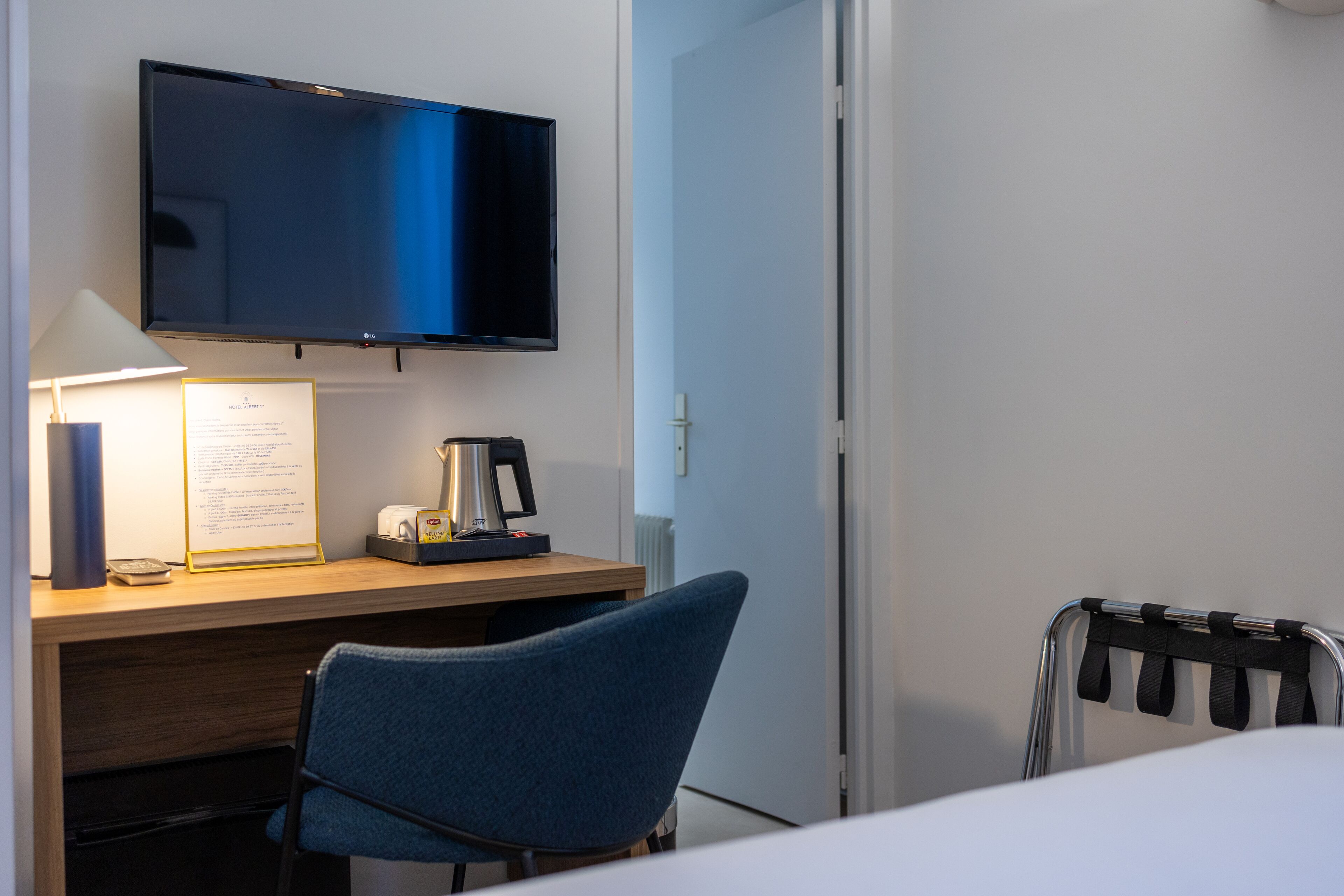 Habitación de hotel con cama, escritorio con lámpara, televisor de pantalla plana y una silla.
