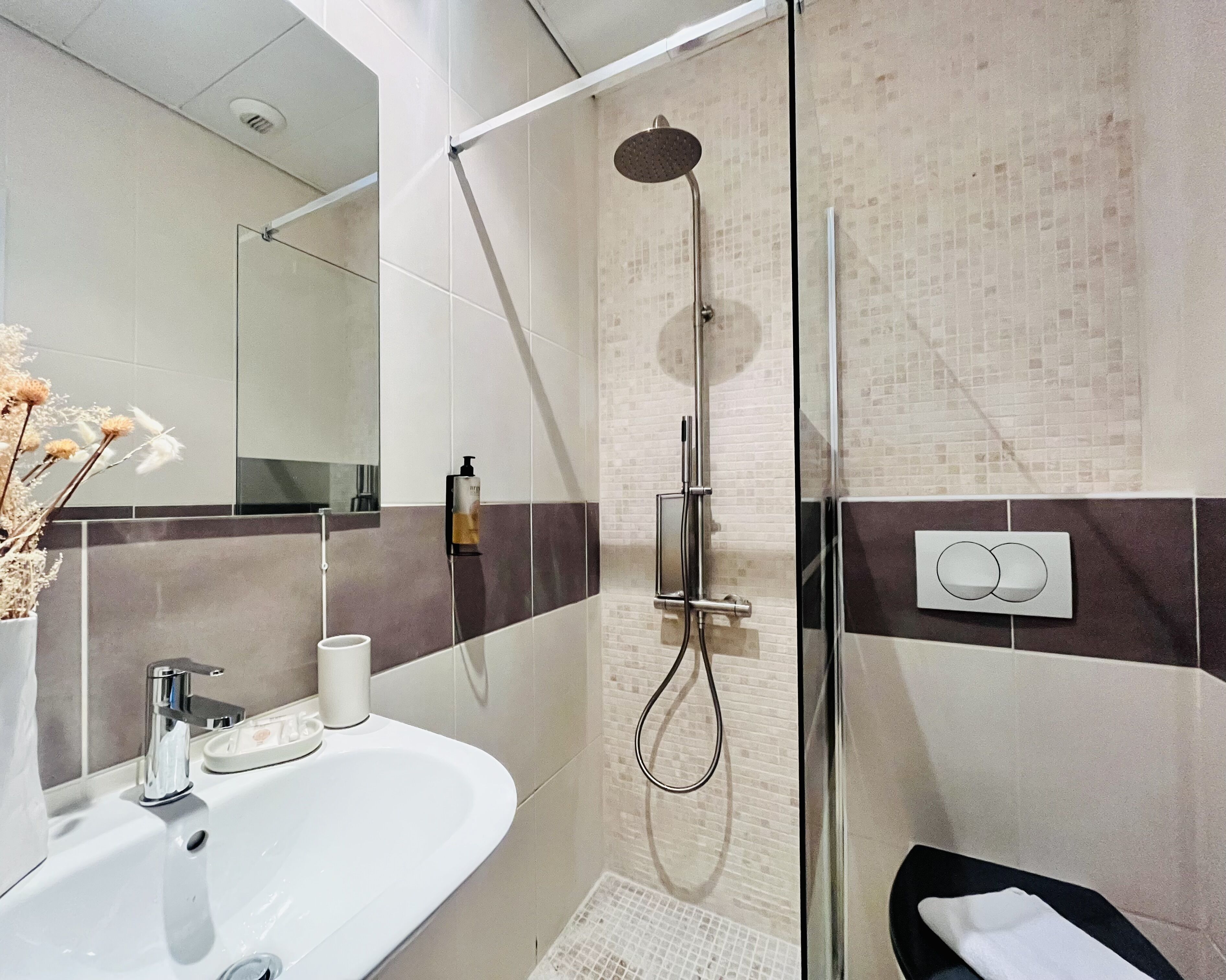 A modern bathroom with a glass shower enclosure, a white sink, and a mirror.