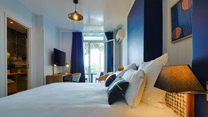 A hotel room with a large bed, a desk, and a chair. There is a TV on the wall and a window with curtains. - Hotel Albert 1er (Cannes)