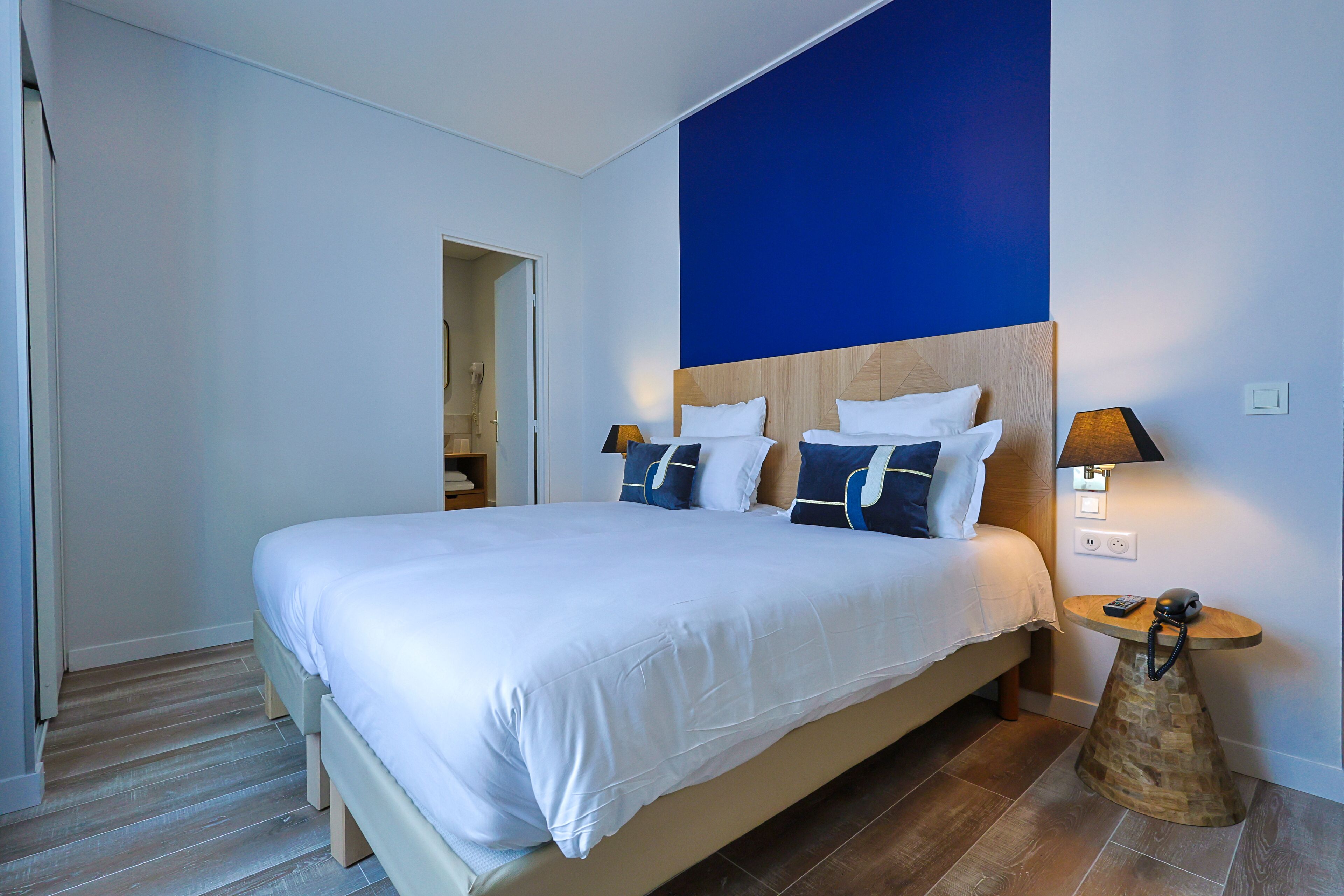 Ein modernes Hotelzimmer mit einem großen Bett, zwei Nachttischen und einer blauen Akzentwand.
