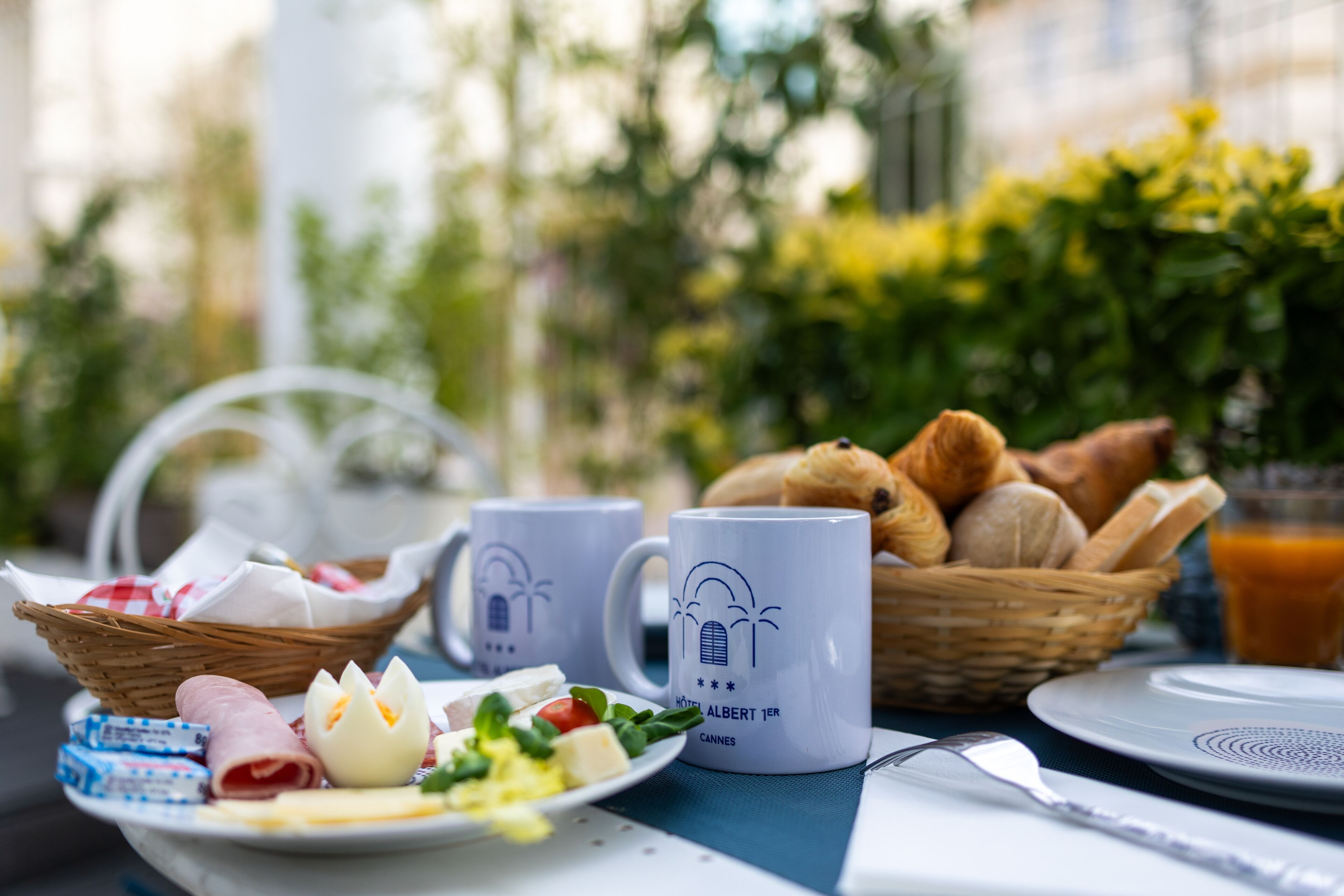 A breakfast table with a plate of food, a basket of bread, a mug, and a glass of orange juice.