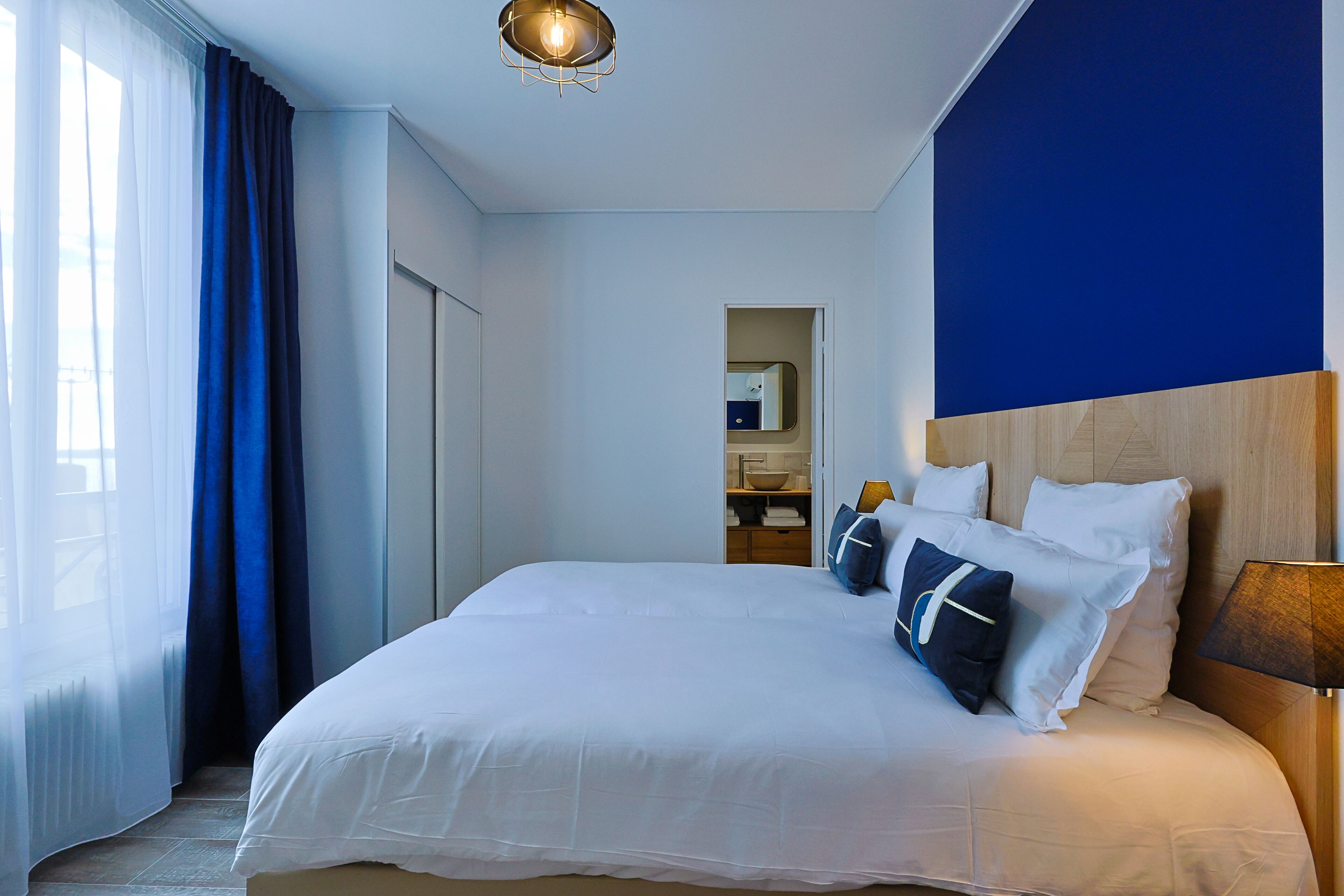 Une chambre d’hôtel avec un grand lit, une table de chevet, une lampe et une vue sur la salle de bain.